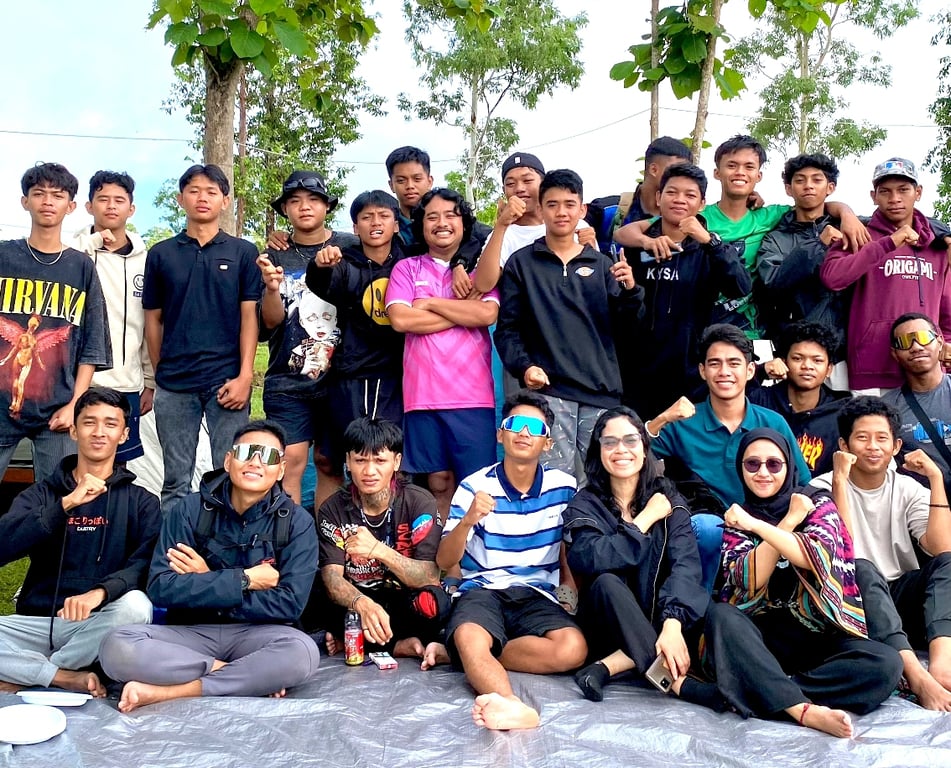 A group of young people posing together outdoors, with some seated on the ground and others standing, expressing camaraderie and unity in Merauke, Papua, Indonesia